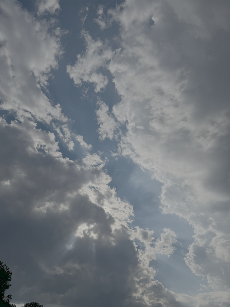 Clouds forming an incredible pattern with what looks like a crevasse down the middle, through which sun rays can be seen.